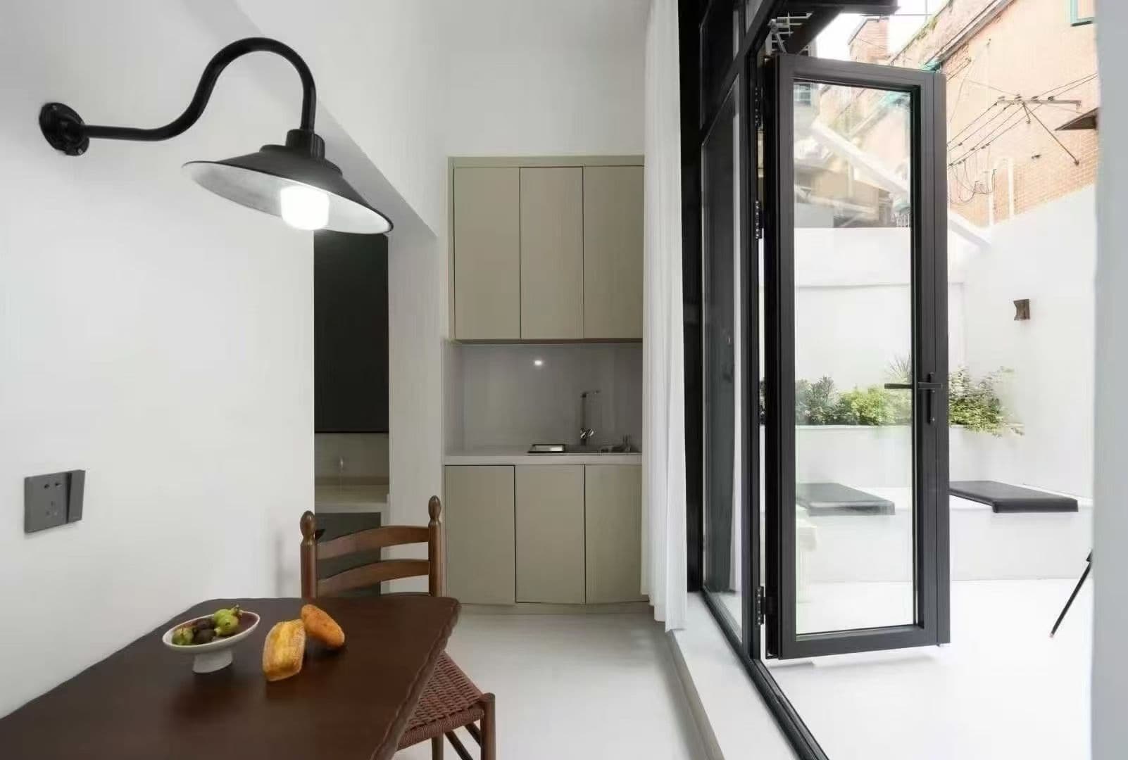 A compact kitchen with a dining area, a built-in bench, and a large sliding glass door leading to an outdoor space.