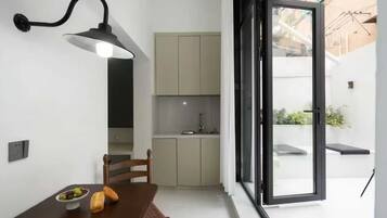 A compact kitchen with a dining area, a built-in bench, and a large sliding glass door leading to an outdoor space.