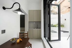 A compact kitchen with a dining area, a built-in bench, and a large sliding glass door leading to an outdoor space.