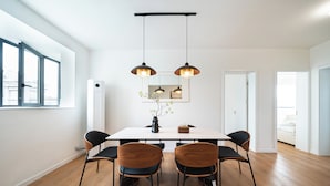 A dining area with a white table, four chairs, two pendant lights, and a vase with flowers. - Tonighy Homestay Jing'an Temple Shanghai (Shanghai)