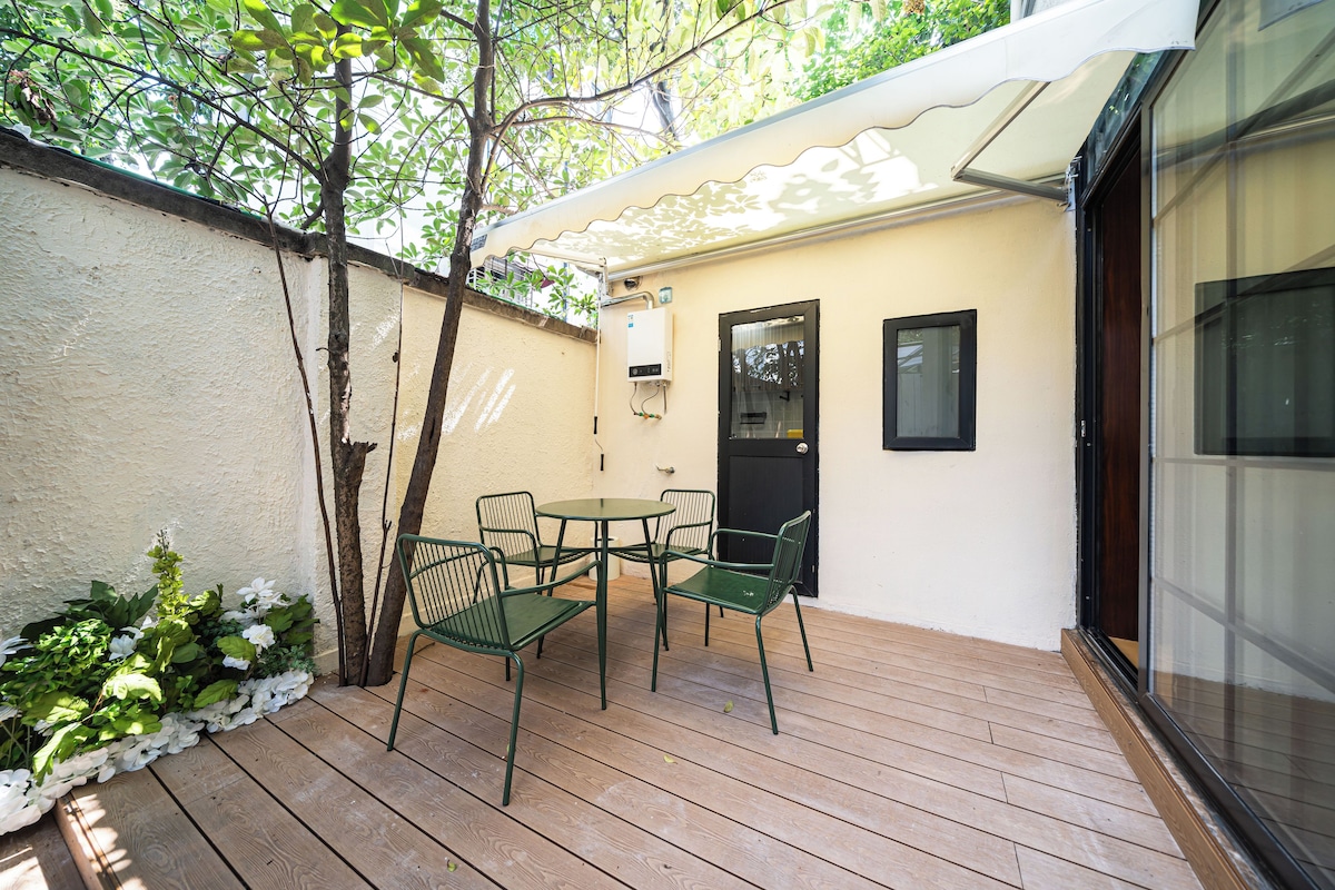 Un pequeño patio al aire libre con una mesa, sillas, una puerta y una ventana.