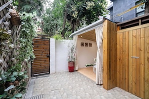 Una verja de madera, una planta en maceta y un muro con tres siluetas de animales.