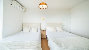 A hotel room with two beds, a ceiling fan, a wall-mounted air conditioner, a bedside lamp, and a door. - Tonighy Homestay Jing'an Temple Shanghai (Shanghai)