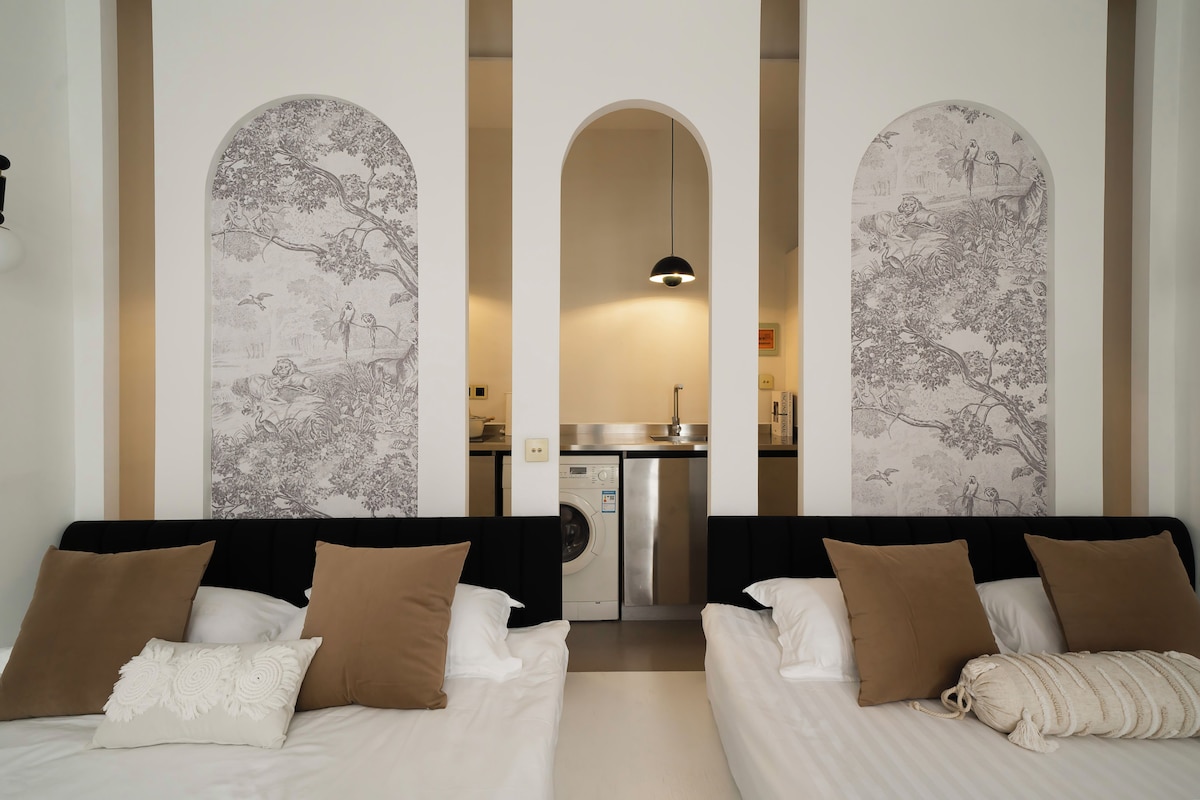 Une chambre d’hôtel avec deux lits, un lave-linge et un coin cuisine.