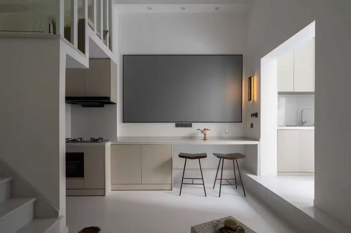 A modern kitchen with a large central island, bar stools, and a built-in oven.