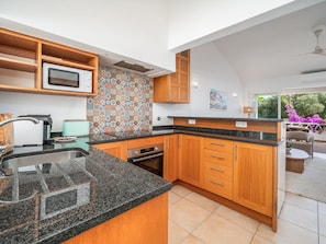 A modern kitchen with wooden cabinets, a microwave, and a patterned backsplash. - Traditional House in Luz, Steps from the Beach (Luz, Lagos)