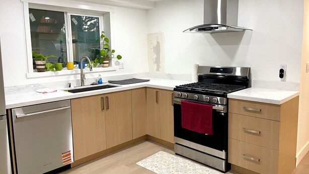 Een moderne keuken met een roestvrijstalen fornuis, een inbouwoven, een spoelbak en houten kastjes.