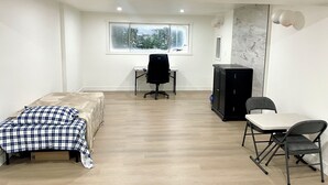 Een kamer met een bed, een bureau, een stoel, een kast en een raam met uitzicht.