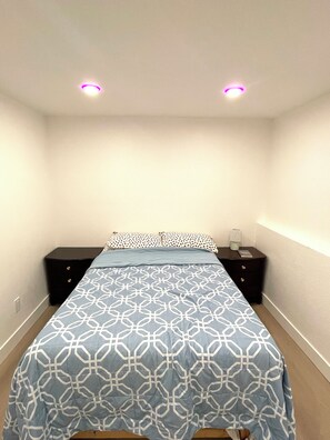 Een slaapkamer met een bed, twee nachtkastjes en een plafondlamp.