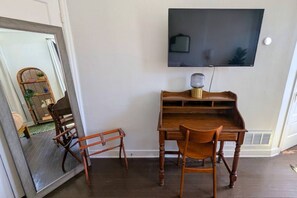 A room with a wooden desk, a chair, a television mounted on the wall, and a mirror reflecting part of the room. - Second Floor, Spacious, 1 Bd Apartment Near Barnes - Stay Smiley Rentals (St. Louis)