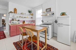A modern kitchen with white appliances, a wooden table, and a red rug. - Second Floor, Spacious, 1 Bd Apartment Near Barnes - Stay Smiley Rentals (St. Louis)