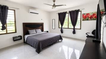 A modern bedroom with a bed, a ceiling fan, a nightstand, and a desk with a computer.