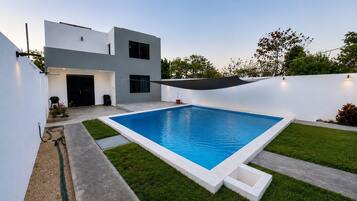 A modern house with a swimming pool, a patio, and a well-maintained lawn.
