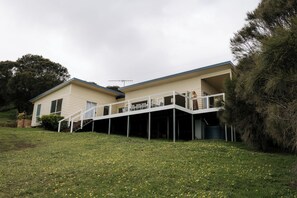 Ein zweigeschossiges Haus mit einer überdachten Terrasse und einer Treppe, die zum oberen Stockwerk führt.