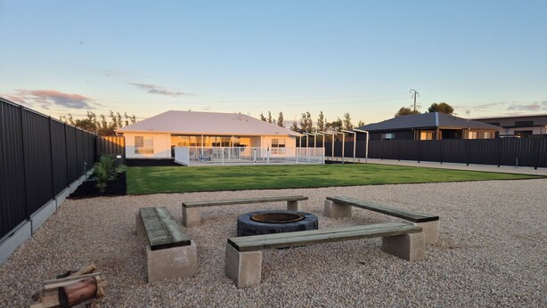 An outdoor patio area with a fire pit, benches, and a gravel surface.