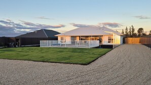 A house with a covered patio, a fenced yard, and a gravel driveway.