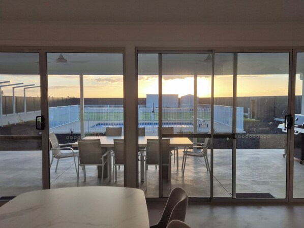 A room with a large sliding glass door leading to an outdoor patio with a pool and a view of a building.