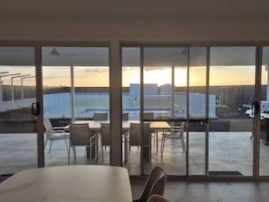 A room with a large sliding glass door leading to an outdoor patio with a pool and a view of a building.