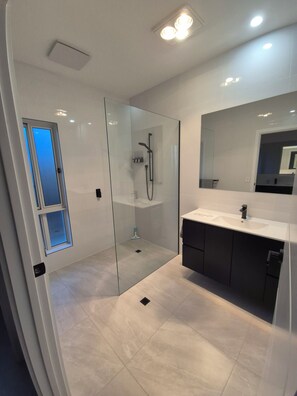 A modern bathroom with a glass-enclosed shower, a large mirror, and a white vanity. - Paringa Escape (Paringa)