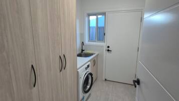 A compact kitchen with a washing machine, a window, and a door.