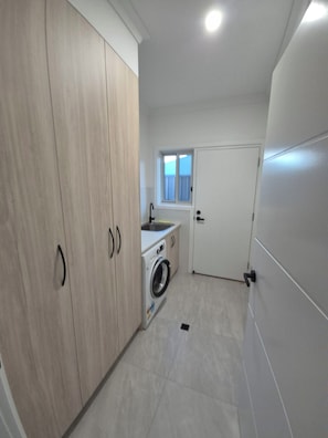 A compact kitchen with a washing machine, a window, and a door.