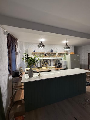 Una cocina moderna con una isla central, luces colgantes y vistas al área de comedor.