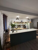 Una cocina moderna con una isla central, luces colgantes y vistas al área de comedor.
