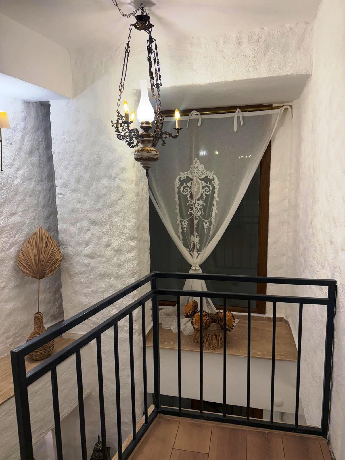 A staircase with a black railing, a white wall, and a decorative chandelier.