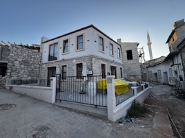A two-story building with a stone facade, a gated entrance, and a staircase leading to the upper floor.