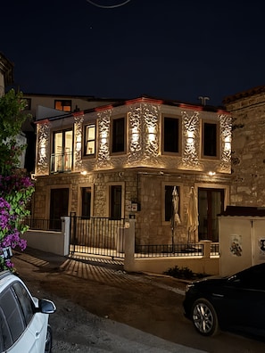 A two-story stone building with illuminated windows and a gated entrance. - Urla Lime Hotel (Urla)