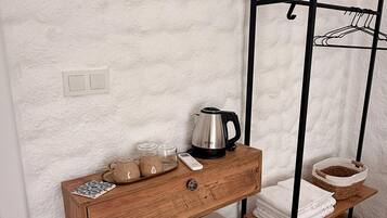 Une petite cuisine équipée comprenant un réfrigérateur, un plan de travail en bois, une bouilloire et un égouttoir.