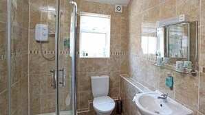 Ein Badezimmer mit einer Duschkabine, einer Toilette und einem Waschbecken mit Spiegel.