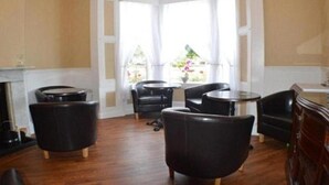 Ein Zimmer mit Erkerfenster, Kamin und einer Sitzecke mit Stühlen und Tisch.
