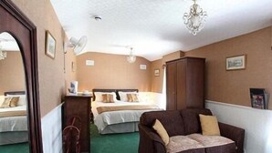 Ein Hotelzimmer mit zwei Betten, einer Schlafcouch, einem Kleiderschrank und einer Kandelaber.