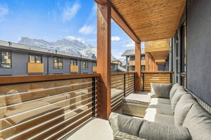 A balcony with a view of mountains, wooden railings, and a sofa. - The Bluebird Suite - Mountain Views - Hot Tub - 2BR (Canmore)