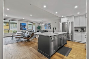 A modern kitchen with a central island, stainless steel appliances, and white cabinetry. - The Bluebird Suite - Mountain Views - Hot Tub - 2BR (Canmore)