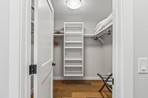 A walk-in closet with a white shelving unit, a hanging rod, and a shoe rack. - The Bluebird Suite - Mountain Views - Hot Tub - 2BR (Canmore)