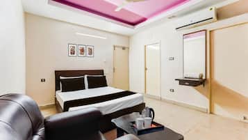 Una habitación de hotel con cama, zona de estar con mesa, ventilador de techo y aire acondicionado de pared.