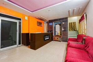 Ein Empfangsbereich mit einer Rezeption, einem roten Sofa und einer Glastür, die auf einen Balkon führt.