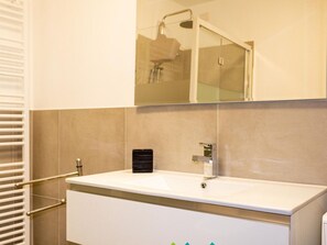 A bathroom with a white sink, a mirror above it, and a shower visible in the reflection. - Holiday Apartment With 2 Bedrooms (Tremosine)