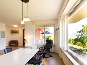 A dining area with a table and chairs, a sofa, a lamp, and a view of the outdoors. - Holiday Apartment With 2 Bedrooms (Tremosine)