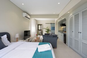 A modern hotel room with a bed, a TV, a desk, a sofa, and a kitchenette. - Enjoy at bait assel by spacey #89 (cairo)