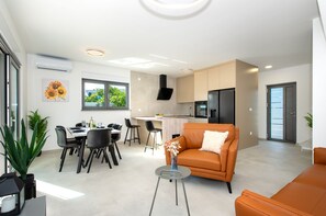 A modern living space with a dining area, kitchen, and seating area. - Holiday home Val (Šibenik)