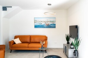 A modern living room with a sofa, a small table with a vase, a TV, and a painting on the wall. - Holiday home Val (Šibenik)