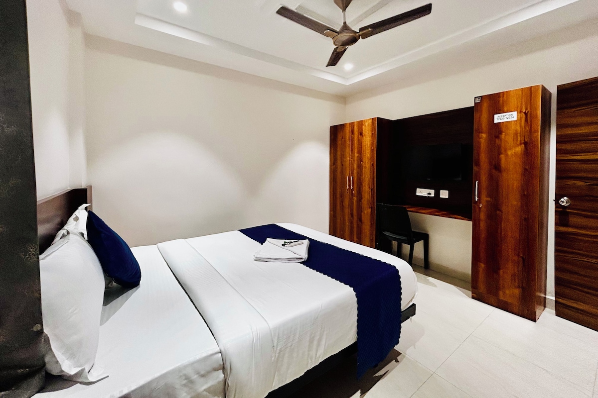 A hotel room with a bed, a desk, a wardrobe, and a ceiling fan.