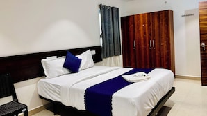 A hotel room with a bed, a chair, a wardrobe, and a ceiling fan. - Orion Signature Hotel  (Hyderabad)