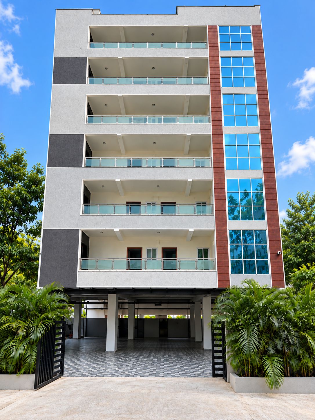 Um edifício de vários andares com telhado plano, varandas e entrada com ladrilhos xadrez.