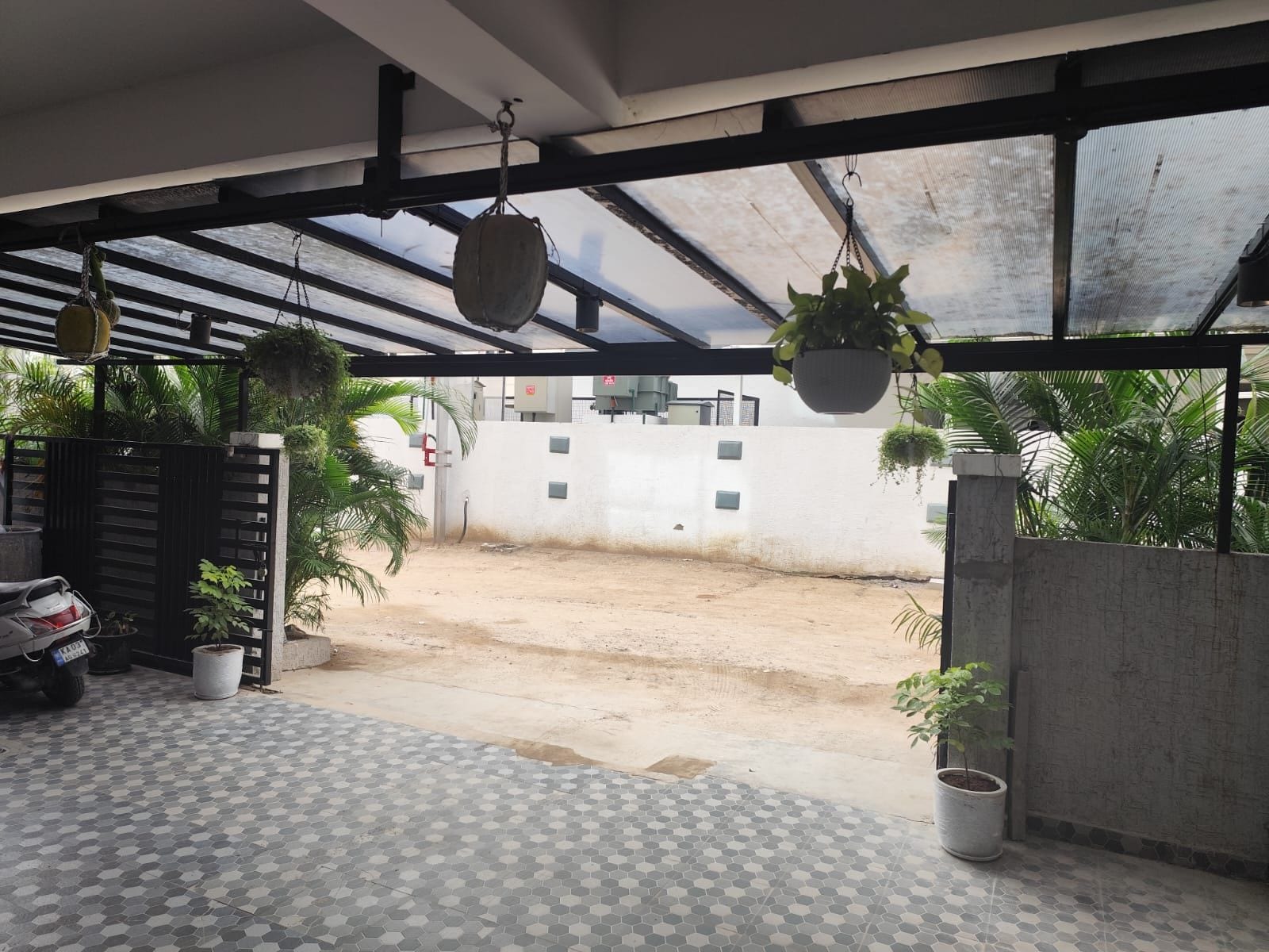 A covered outdoor area with hanging planters, a tiled floor, and a view of a residential street.