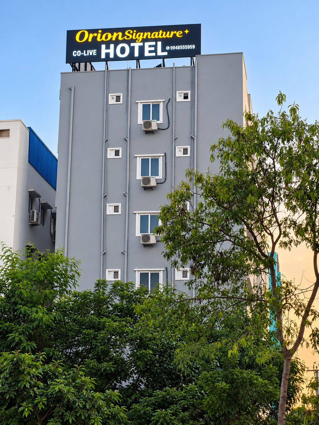 Un edificio de hotel con un letrero que dice 'OrionSignature Hotel' y un número de teléfono.