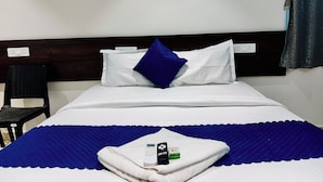 A hotel room with a bed, a chair, and a blanket. - Orion Signature Hotel  (Hyderabad)